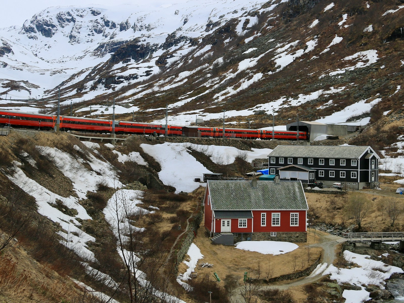 a red train traveling down tracks next to a snow covered mountain